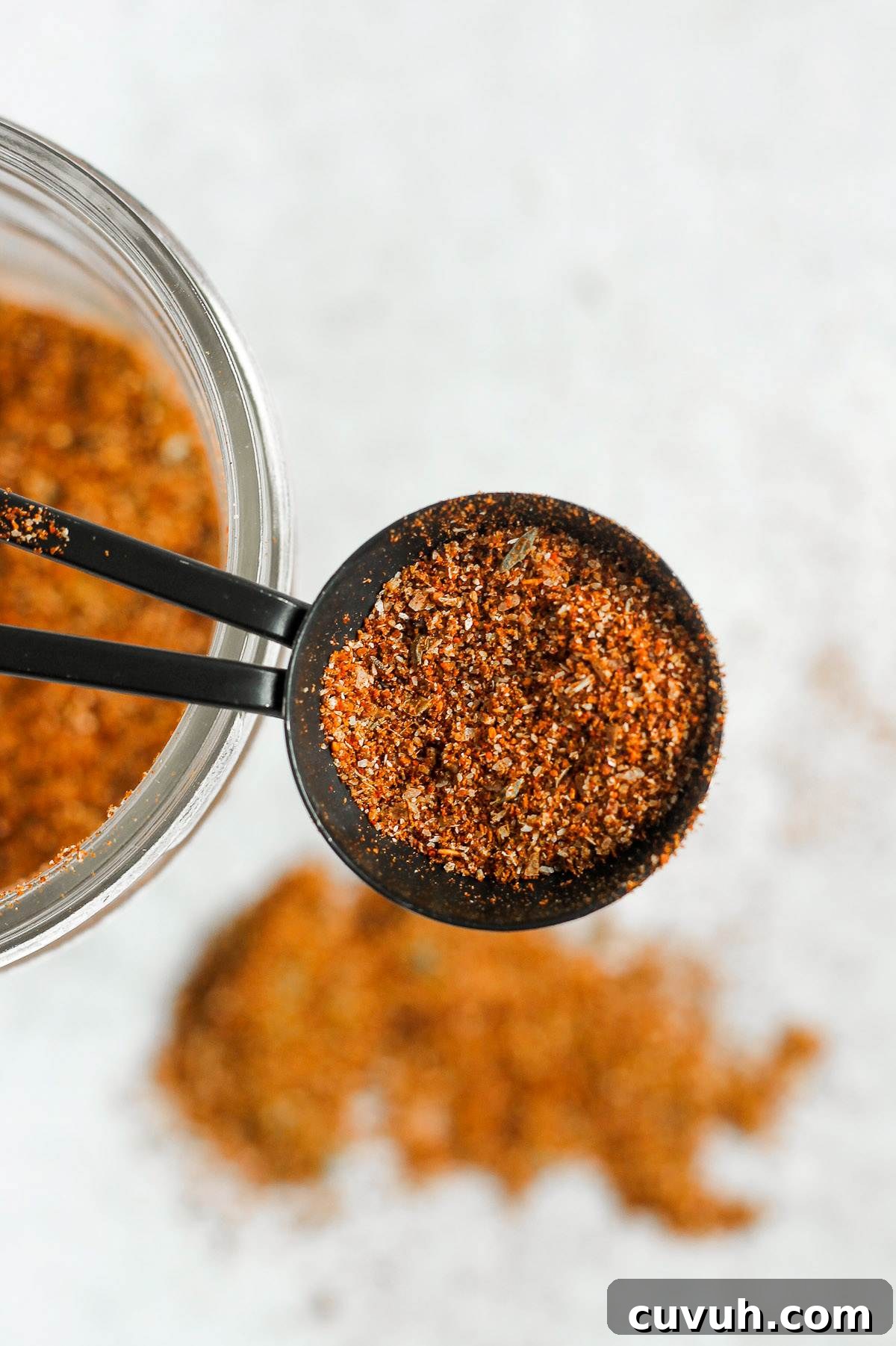 Clean-Eating Taco Seasoning Mix for Flavorful Homemade Tacos 2 Measuring tablespoon filled with taco seasoning with a mason jar of taco seasoning in the background.