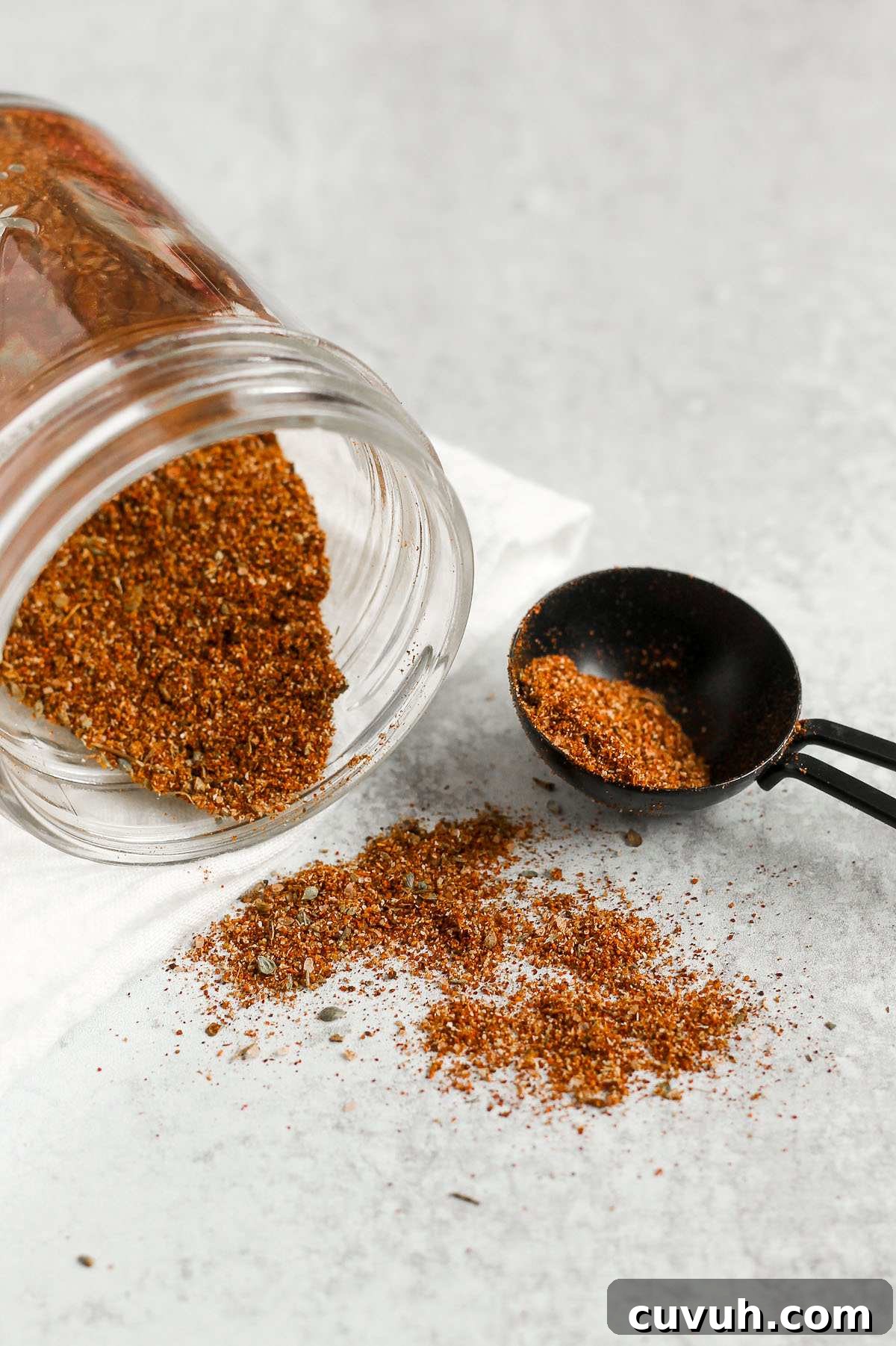Clean-Eating Taco Seasoning Mix for Flavorful Homemade Tacos 6 Taco seasoning spilling from a mason jar with a tablespoon on the side filled with taco seasoning.