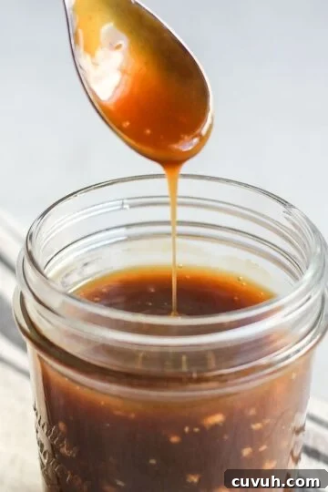 Teriyaki sauce dripping from a spoon over a mason jar filled with teriyaki.