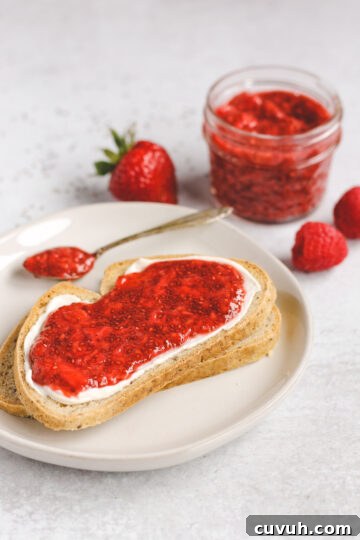 Side view of two slices of toast, stacked on top of each other; top toast with cream cheese and jam spread on it