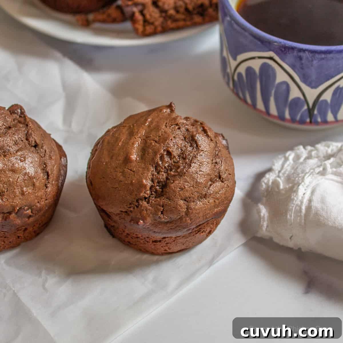 Chocolate muffins next to a cup of coffee.