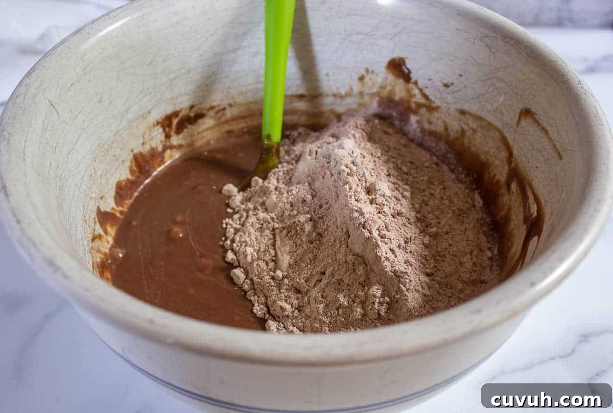 Flour mixture on top of a chocolate batter in a large bowl.