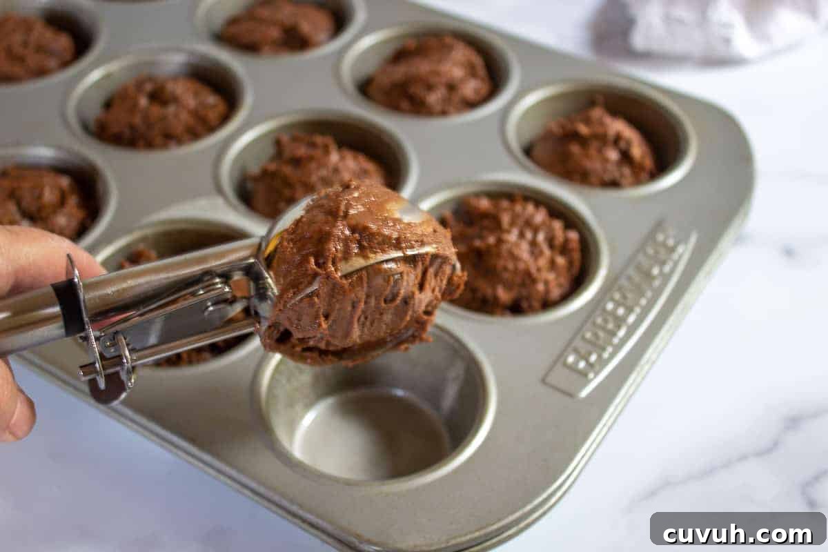 Scooping muffin batter into muffin tins.