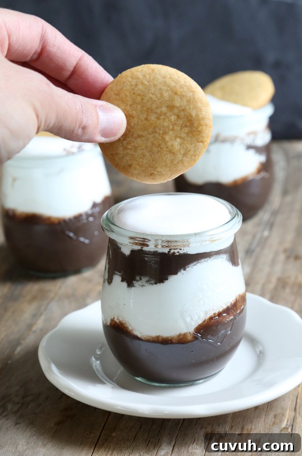 Gluten Free S'mores Parfaits Cookie being held over a S'mores Parfait