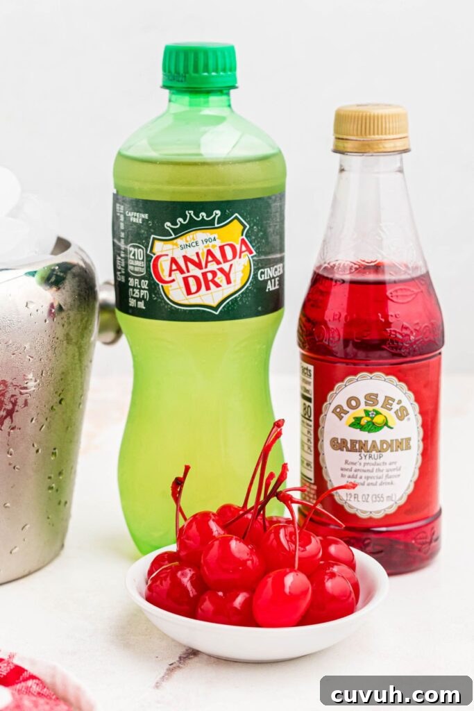 Ingredients needed to make Shirley temple drink of Ginger ale, grenadine, and cherries on a marble table. 