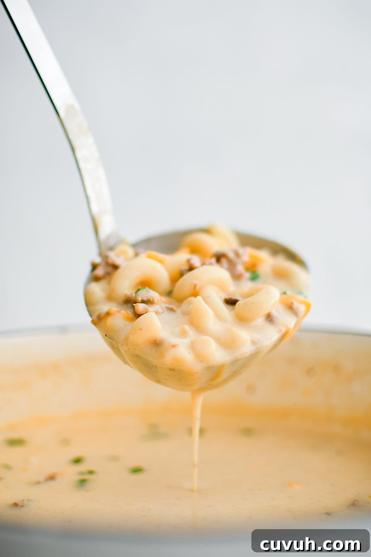 cheesy hamburger noodle soup on a ladle