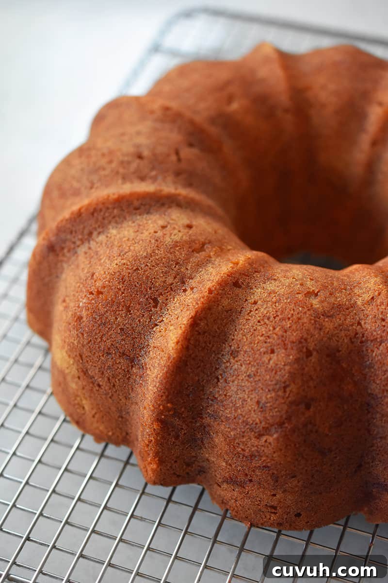 An apple Bundt Cake cooling on a cooling rack after the bundt pan has been removed.