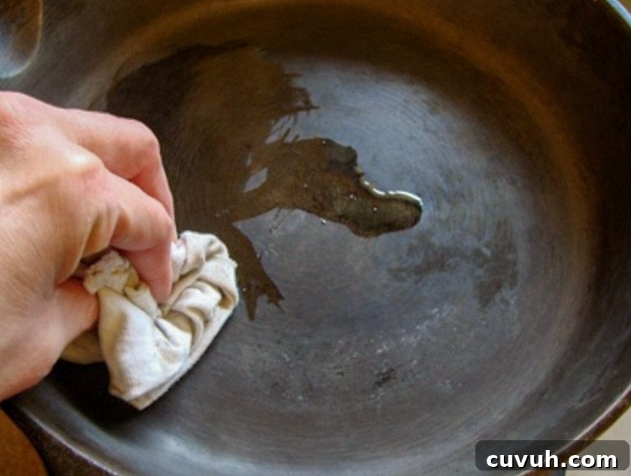 How to Clean and Care for a Cast Iron Skillet: Tips for Lasting Seasoning 9 rubbing cast iron pan with bacon grease