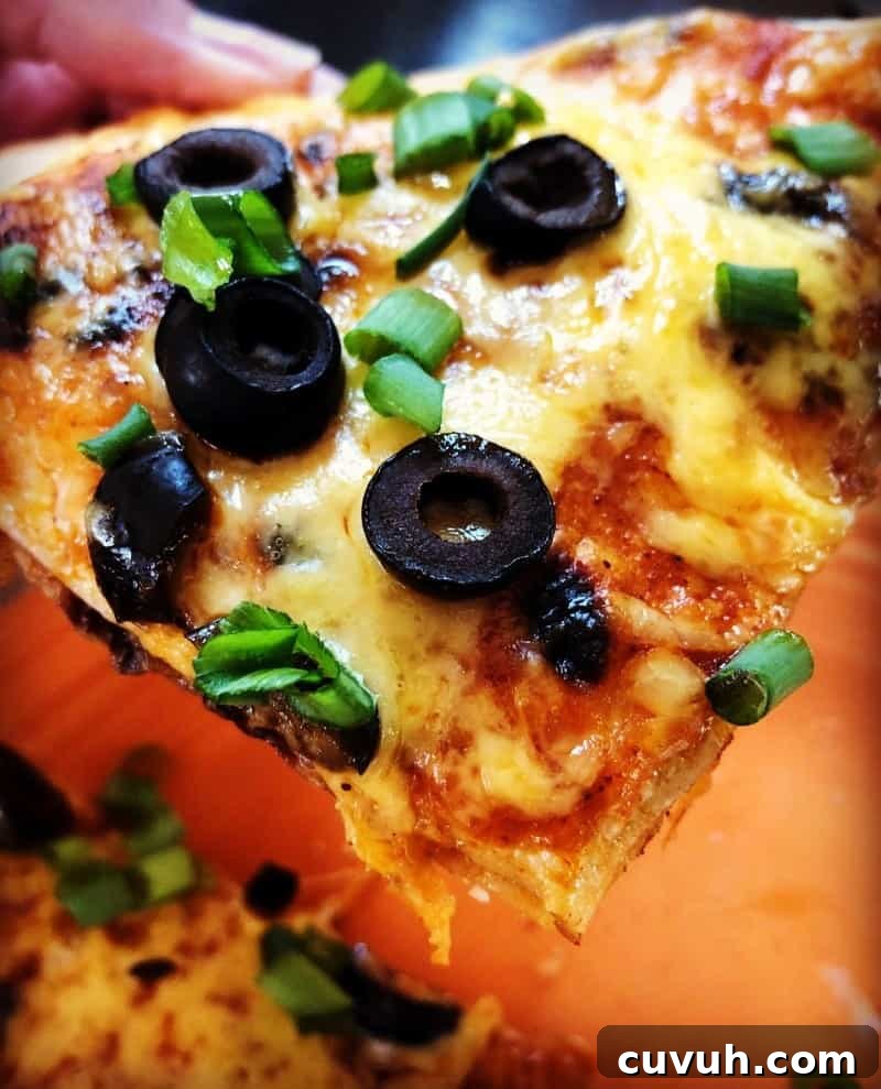 Copycat Taco Bell Mexican Pizza Recipe to Make at Home 9 homemade mexican pizza slice with cheese, olives and green onions.