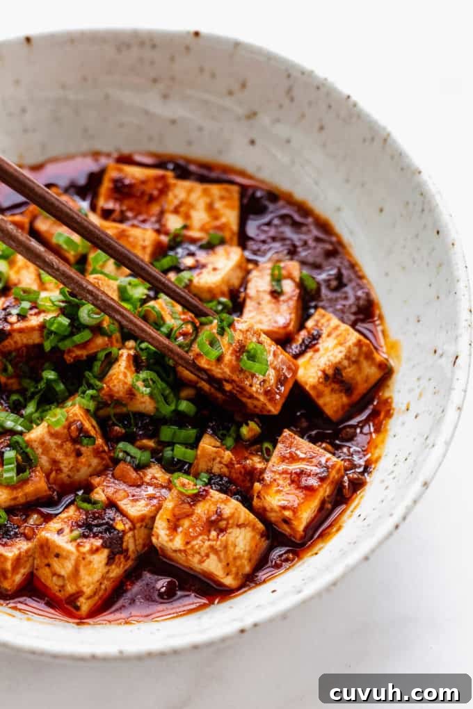 Chopsticks picking up a cube of mapo tofu