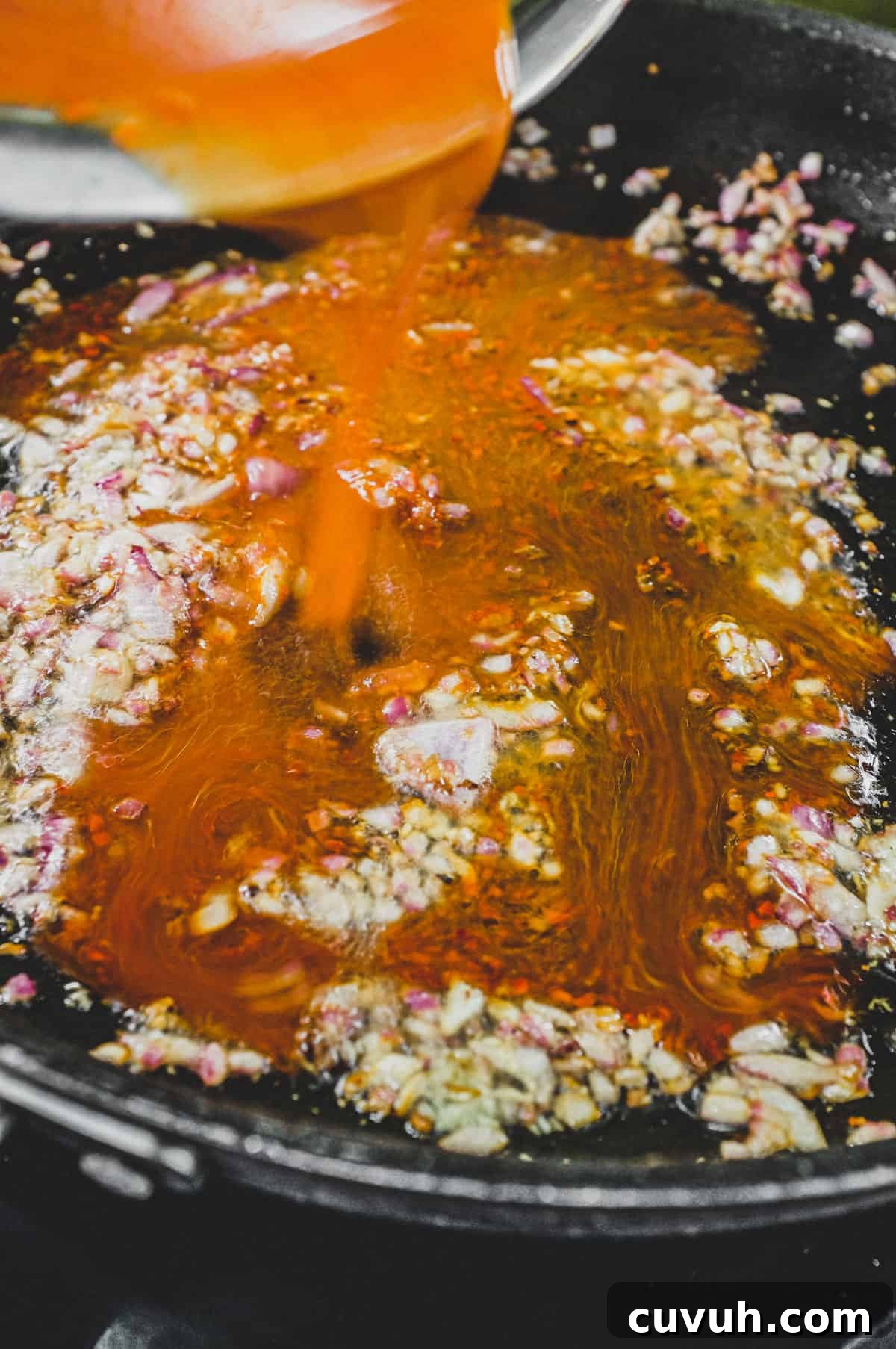 Sauce being prepared Korean chilli with soy, sugar and water poured over lightly fried onion