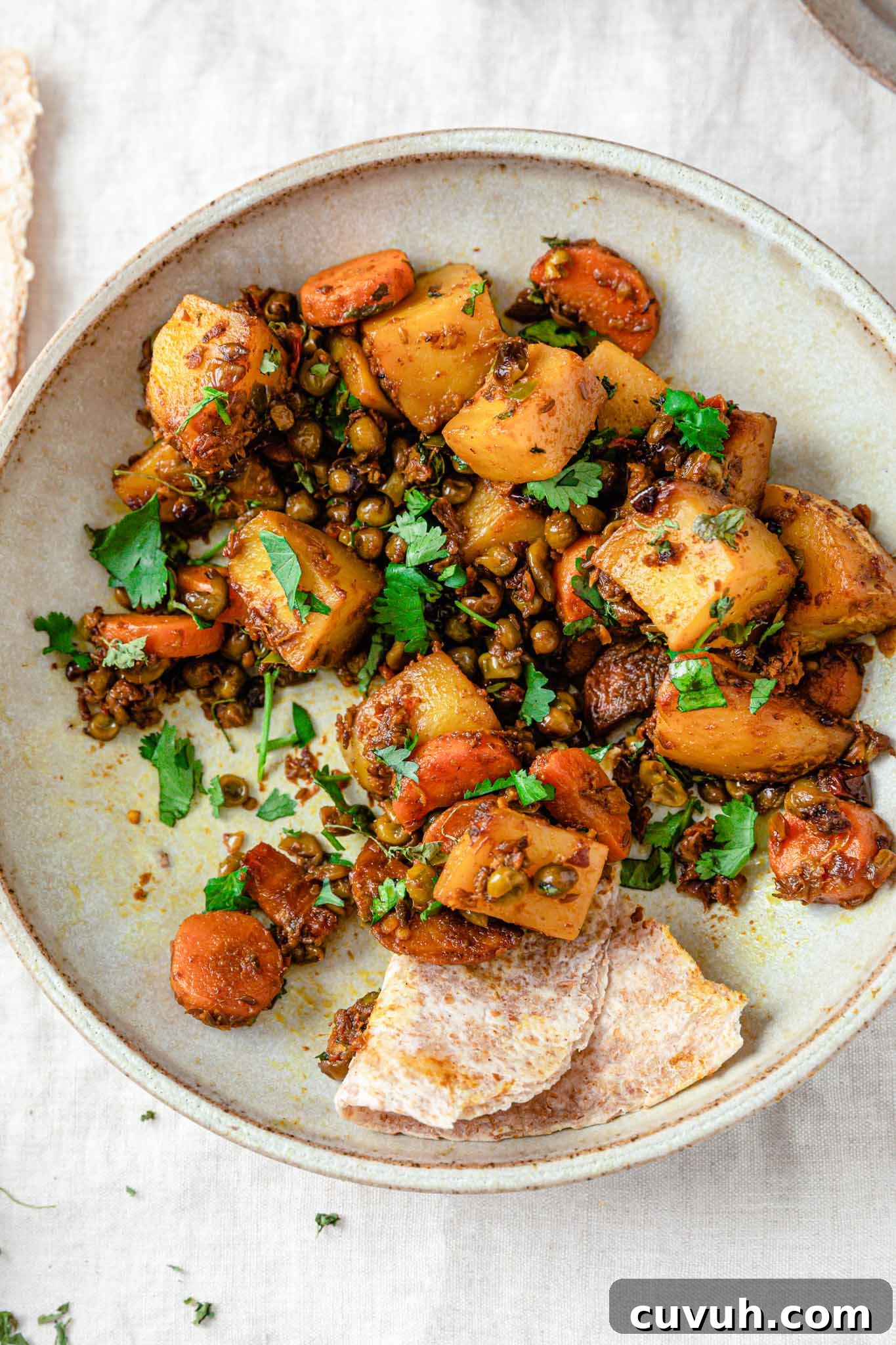Closeup of curried mixed vegetables inside a beige bowl