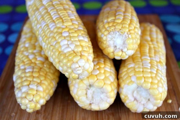 Fresh Corn 5 ears of fresh corn stacked on a cutting board with a blue and green polka dot tablecloth underneath