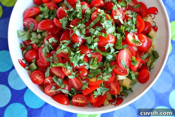 Basil fresh basil added to a bowl of tomatoes set on a blue and green polka dot tablecloth