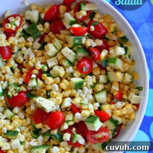 overhead shot of white bowl of fresh corn, tomato and zucchini salad set on a blue and green polka dot tablecloth