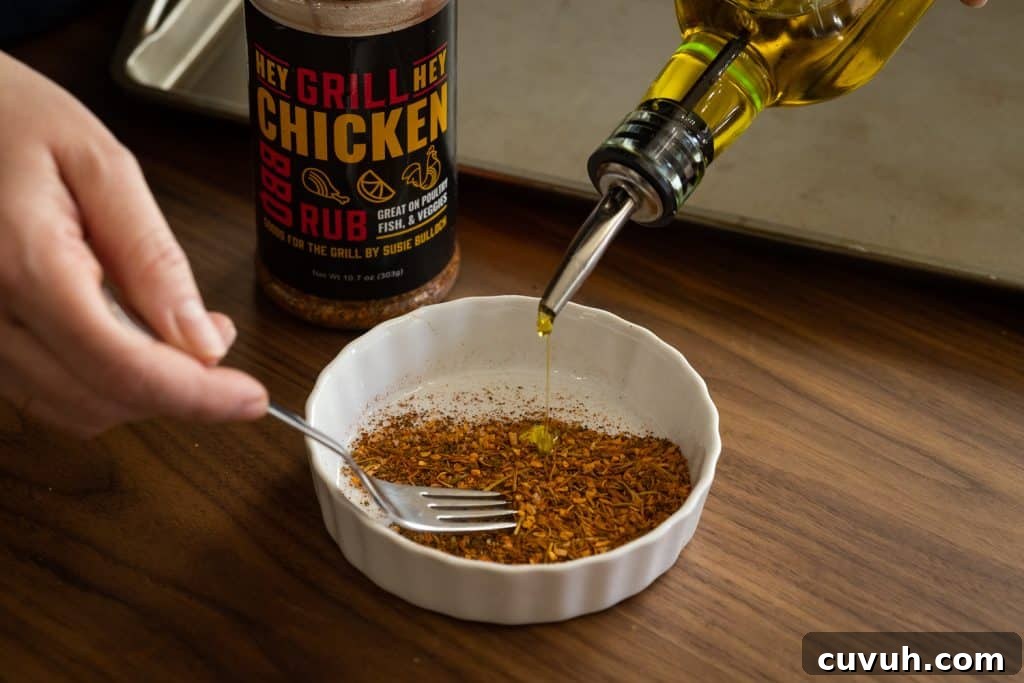 Crispy Grilled Beer-Can Chicken Recipe for Juicy Poultry 3 Olive oil and Hey Grill Hey Chicken Rub being mixed together in a small bowl.