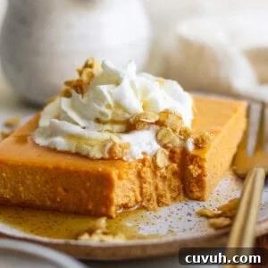 A slice of pumpkin dessert topped with whipped cream and granola on a plate, with a fork beside it. A small portion is missing from the dessert.