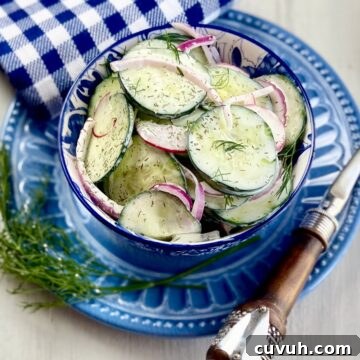 Creamy cucumber salad in a blue and white bowl.
