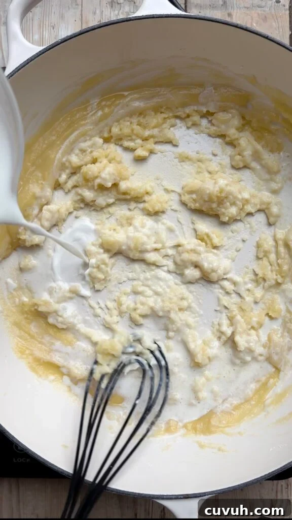 Creamy Baked Macaroni and Cheese Casserole 6 Milk pouring into a pan filled with roux.