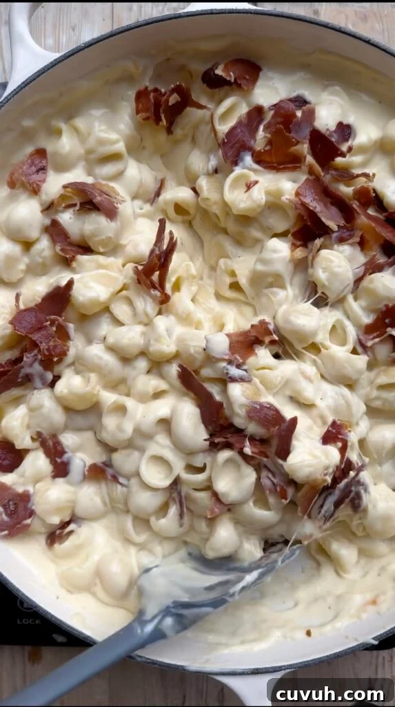 Creamy Baked Macaroni and Cheese Casserole 9 Noodles and crispy prosciutto being stirred into a creamy-cheese sauce.