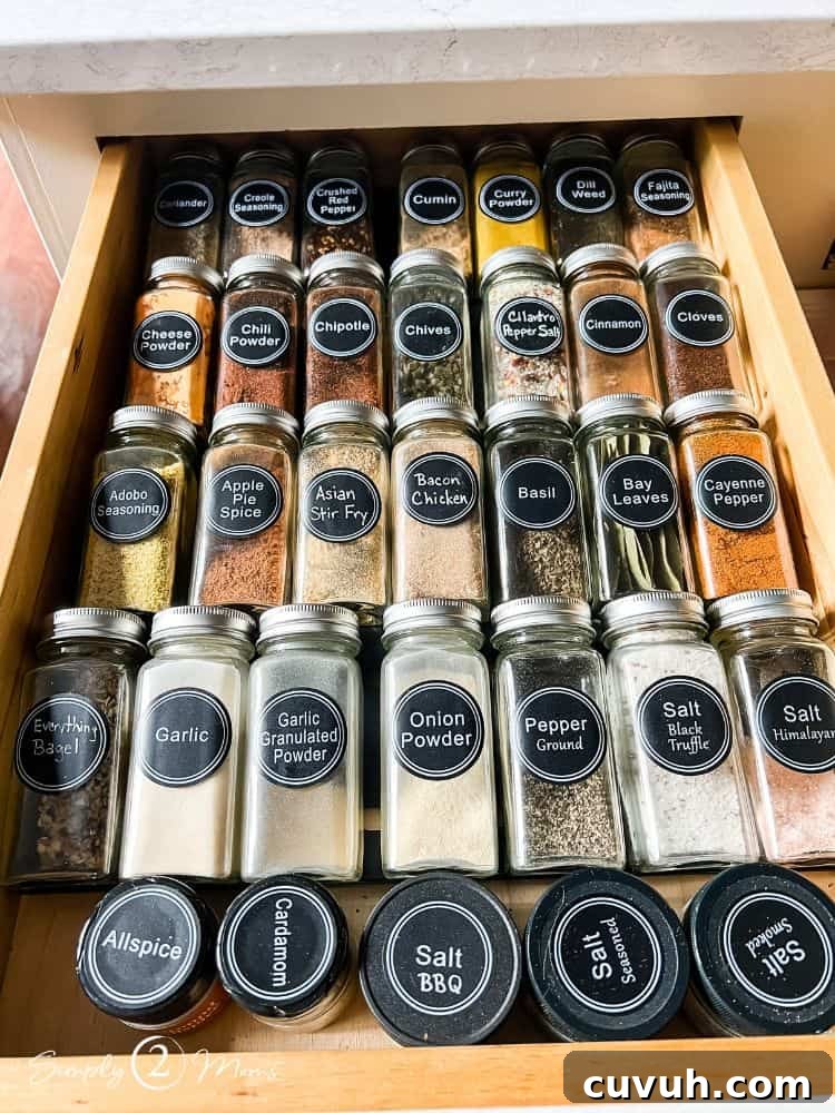 Drawer with rows of glass spice jars with round printed black labels.