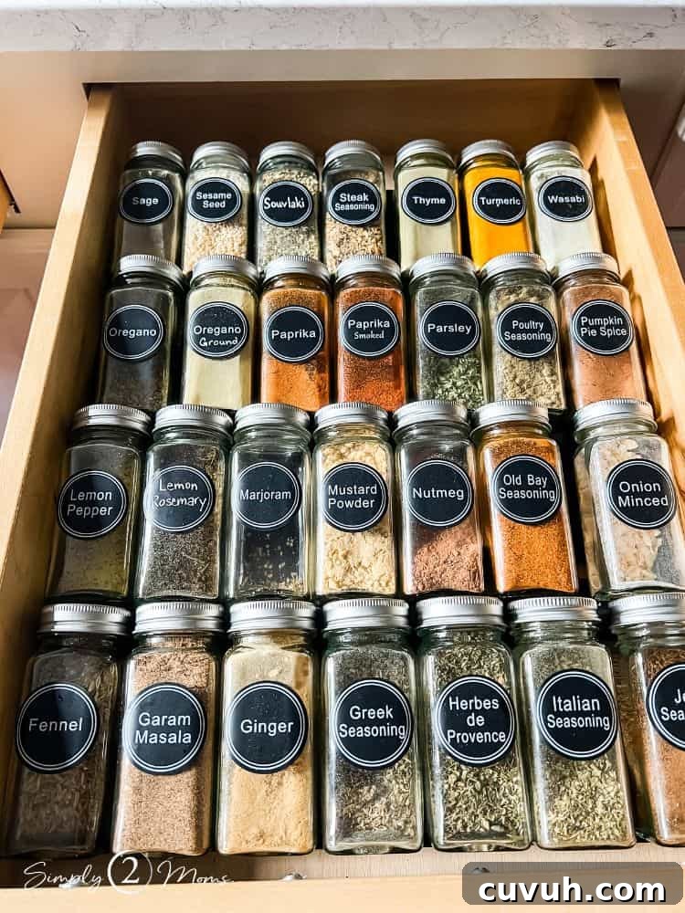 Drawer with rows of glass spice jars with round printed black labels.