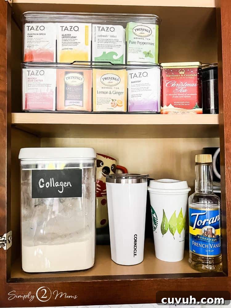 Cabinet with container of collagen and coffee cups. Second shelf has clear plastic tea bag organizer boxes.