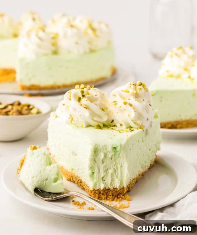 a slice of no bake pistachio cheesecake on a white plate, with a bite taken out of it.