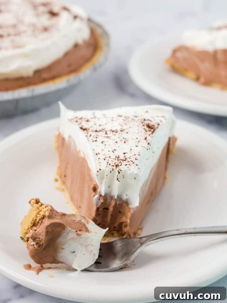 A slice of chocolate Dream Whip pie with a bite removed from the tip of it by a fork.