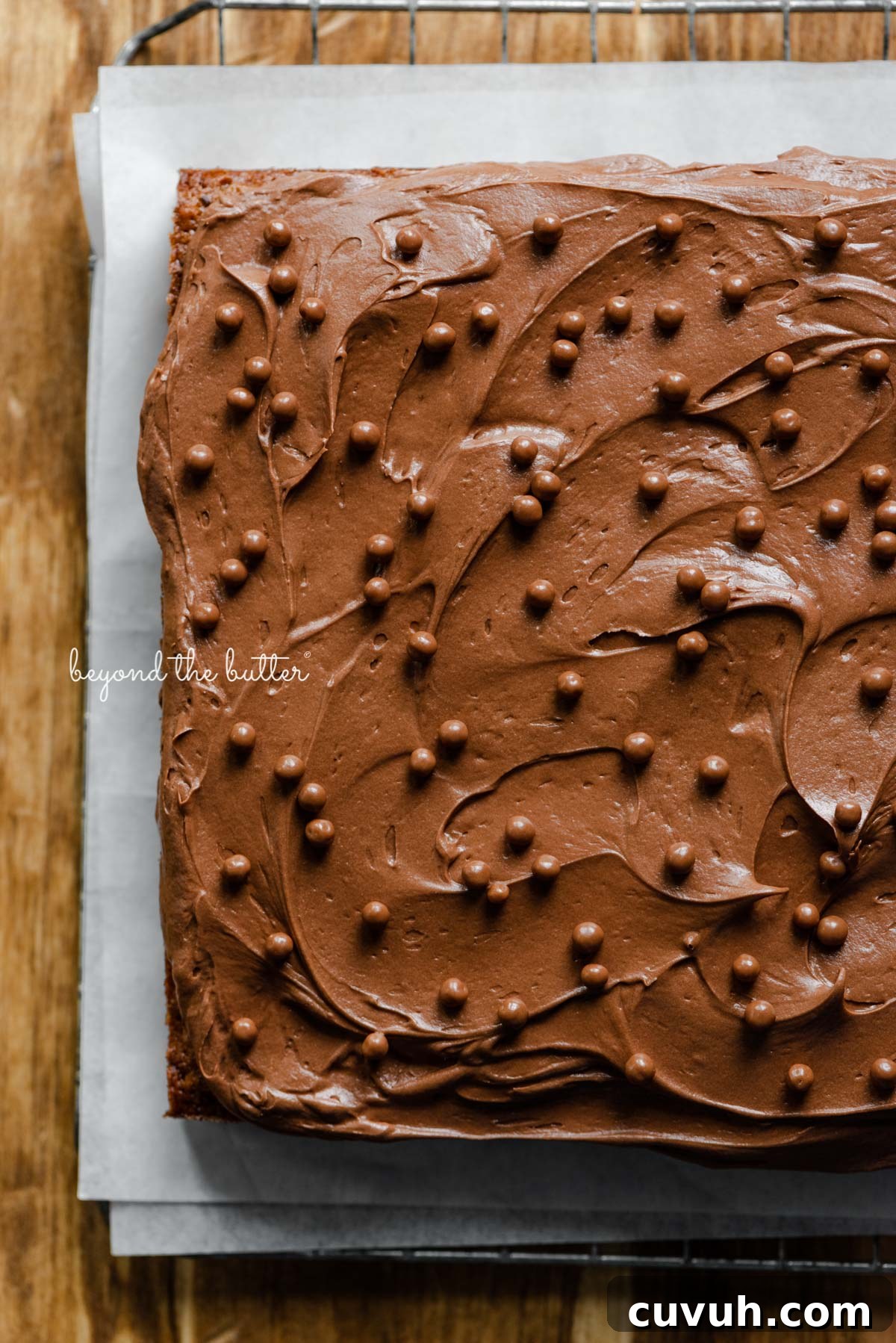 Banana chocolate chip snack cake with chocolate cream cheese frosting on parchment paper and wire cooling rack