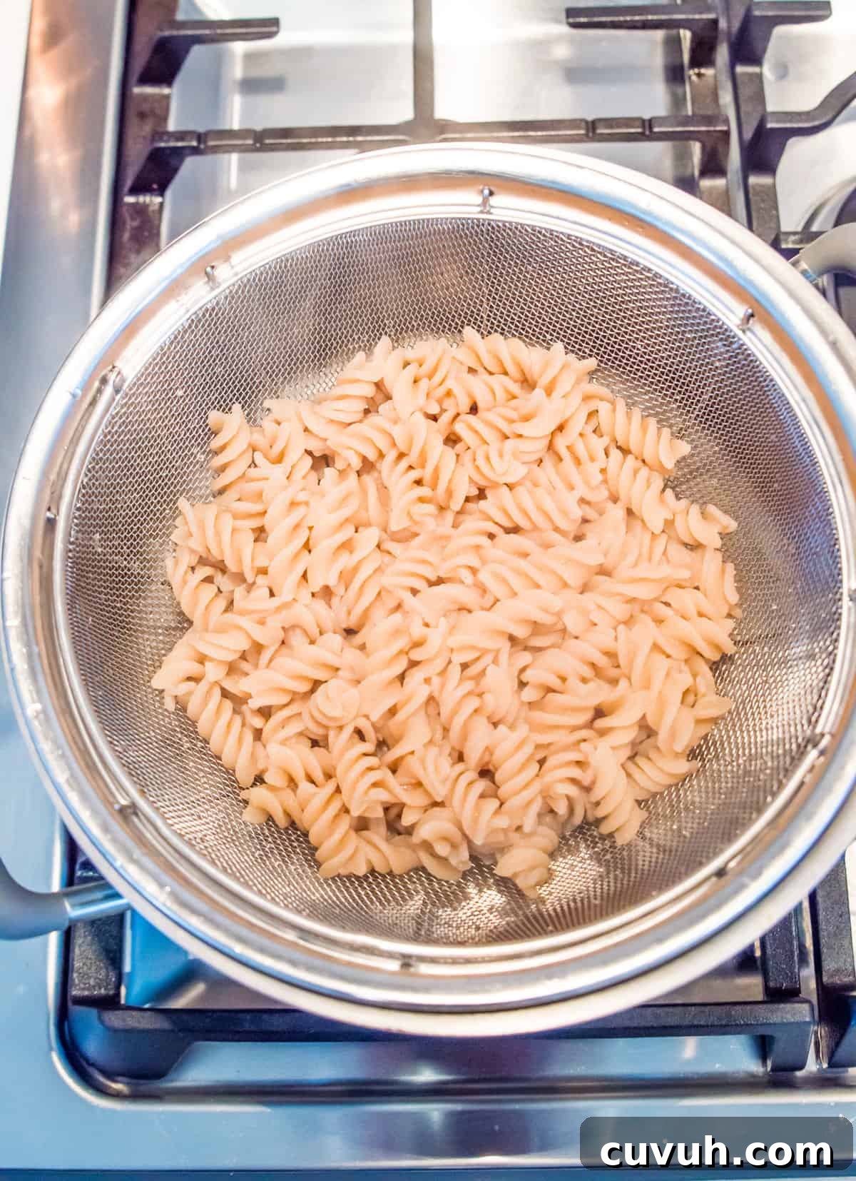 4-Ingredient Tuna Pesto Pasta Recipe – Ready in Minutes 4 A metal colander with cooked spiral noodles in it.