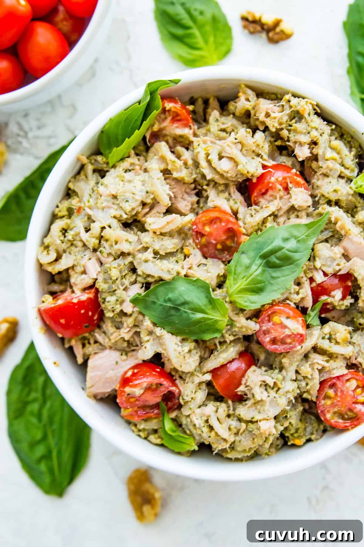 4-Ingredient Tuna Pesto Pasta Recipe – Ready in Minutes 8 A bowl of tuna pasta salad topped with fresh basil leaves.