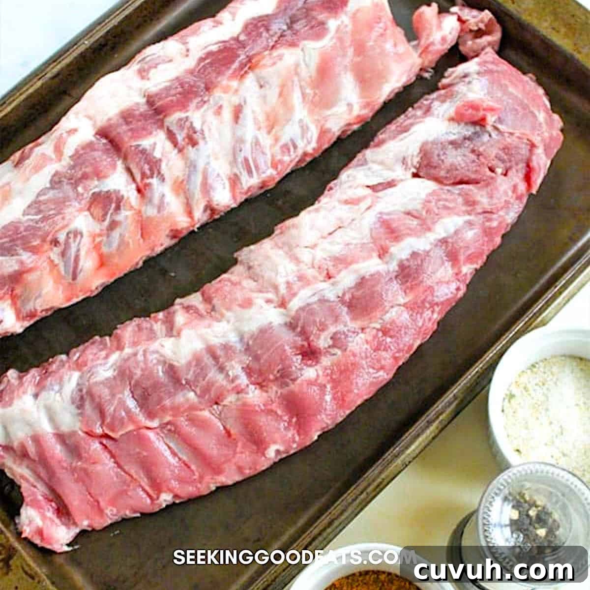 Placing two racks of ribs on a large baking sheet.
