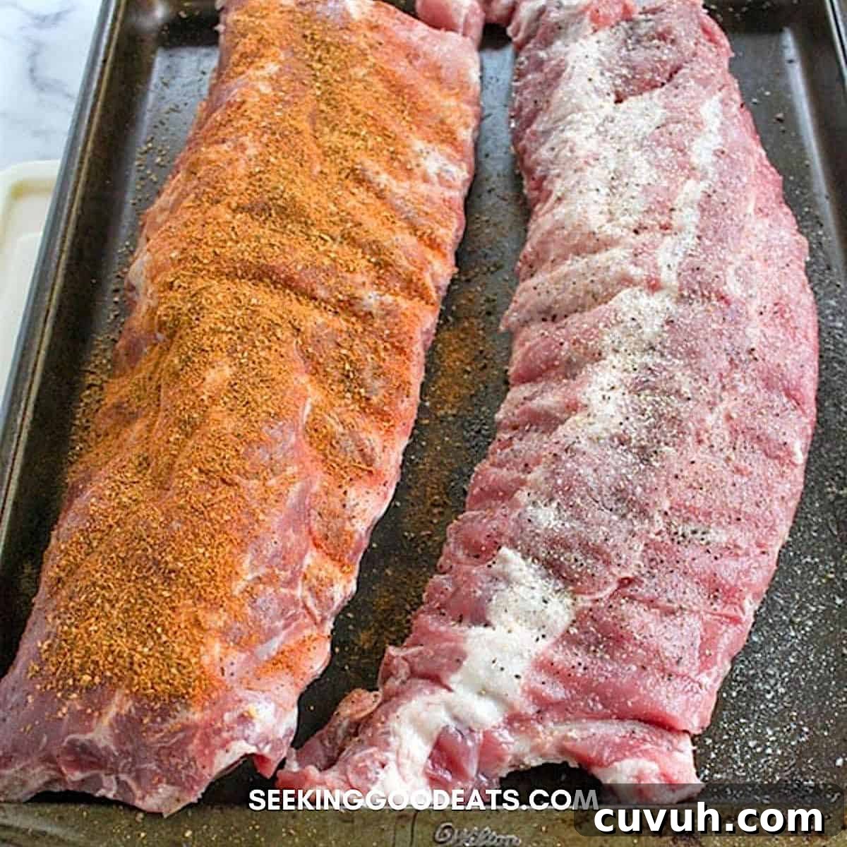 Sprinkling dry rub onto two racks of baby back ribs.