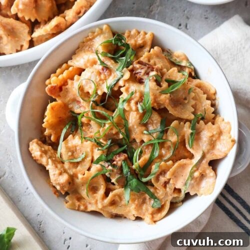 bowl with creamy chicken ricotta pasta topped with fresh basil.