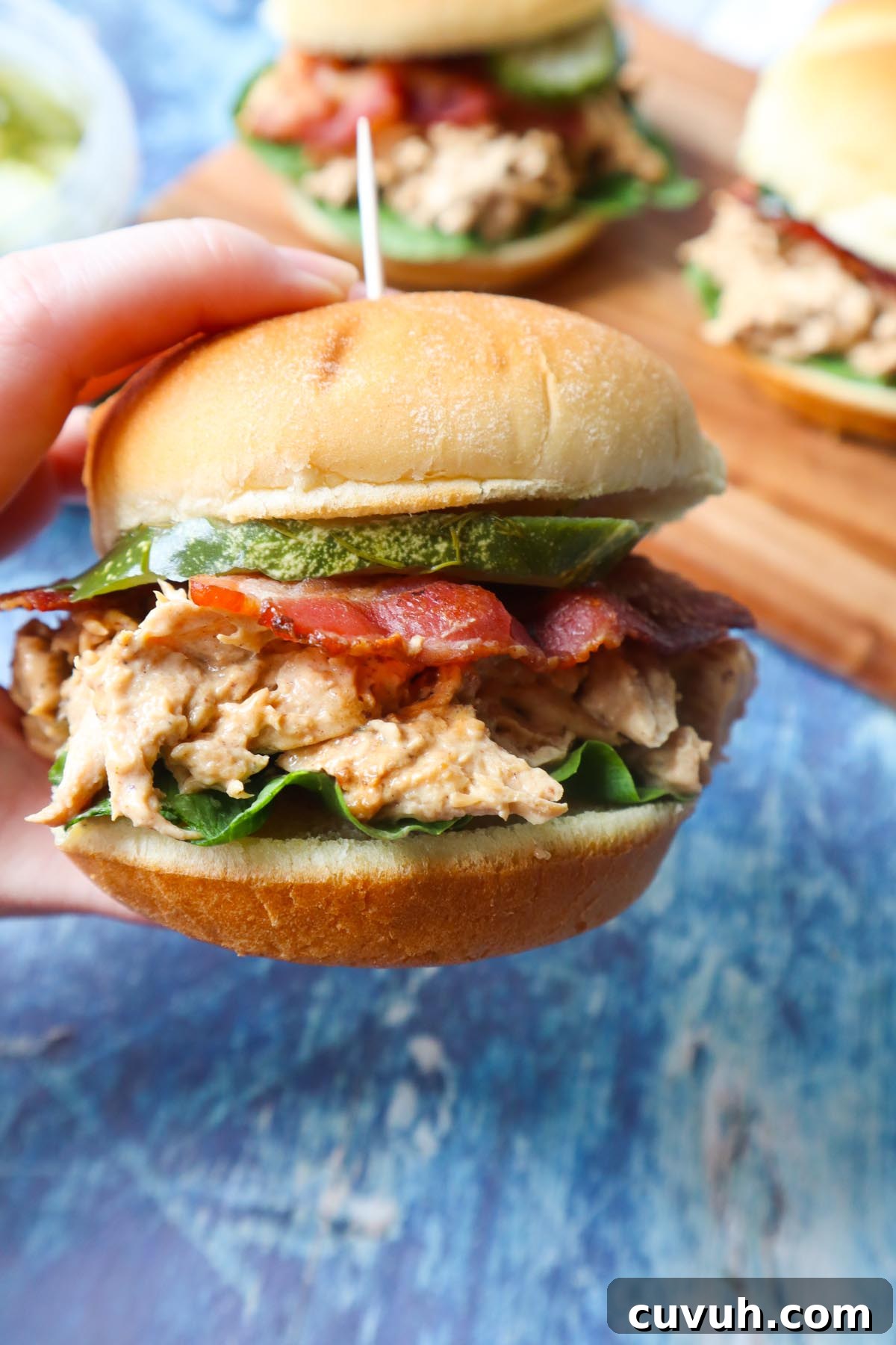 Smoked Gouda Chicken Bacon Ranch Sandwich Recipe 10 hand holding a chicken bacon ranch sandwich with ranch shredded chicken, lettuce, bacon, and pickle