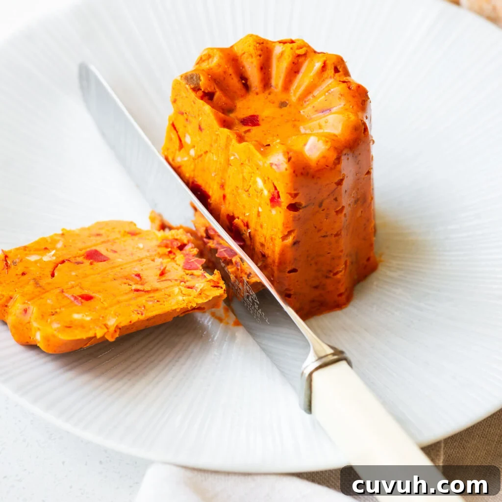 Shaped harissa butter on a small plate sliced with a knife.