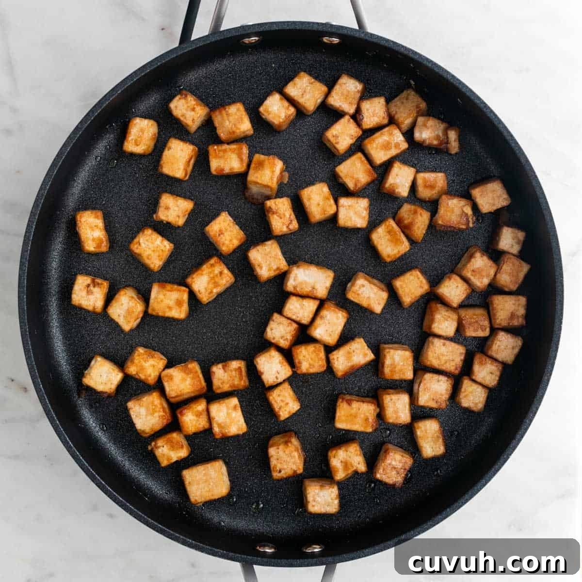 Sticky Teriyaki Tofu Bowl with Sesame and Scallions 7 Sautéed tofu cubes in a skillet.