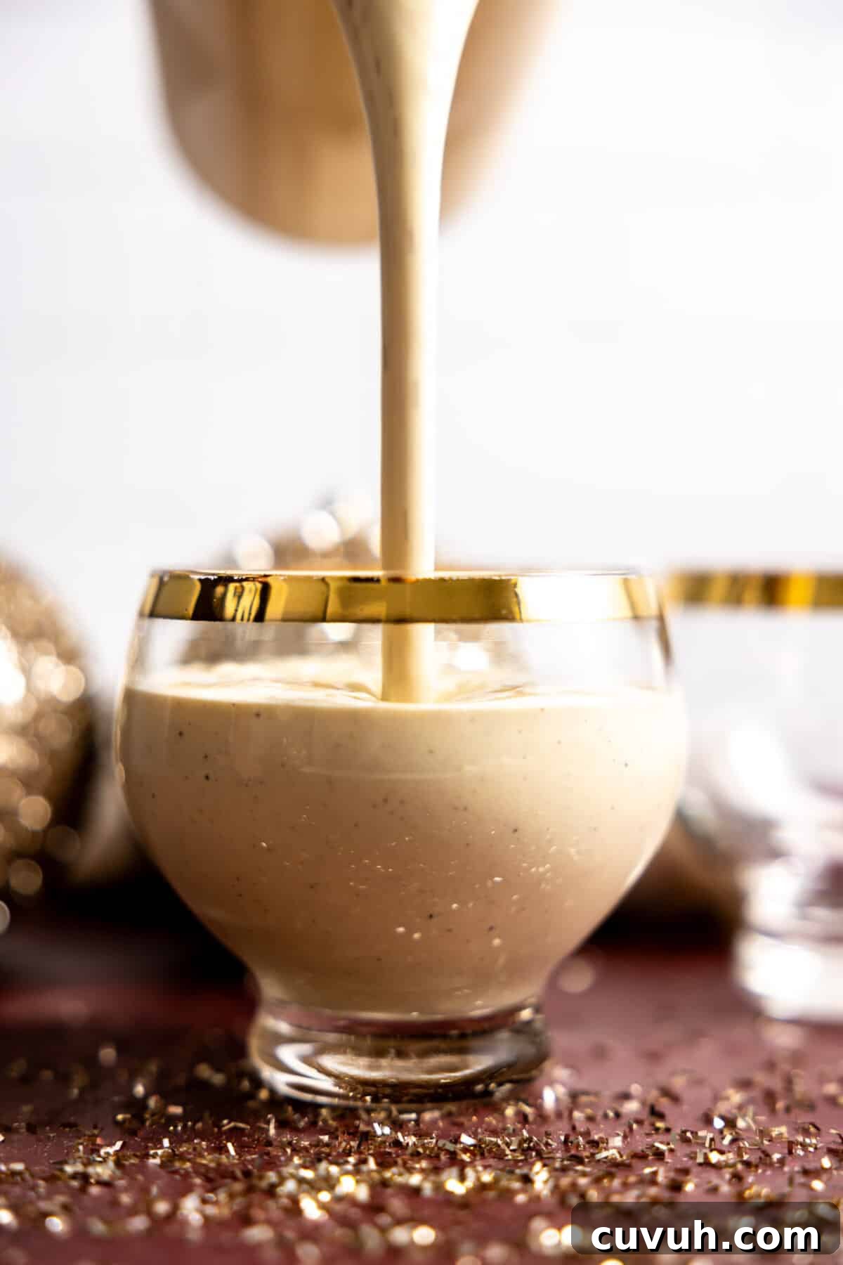 Pouring eggnog into a glass to serve.