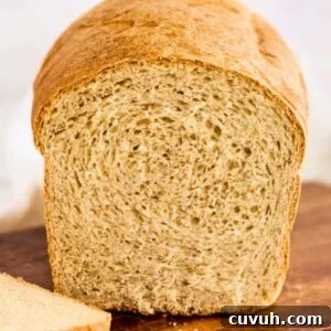 finished loaf of honey wheat bread sliced on cutting board