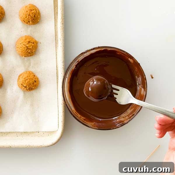 Dipping the truffle in melted chocolate.
