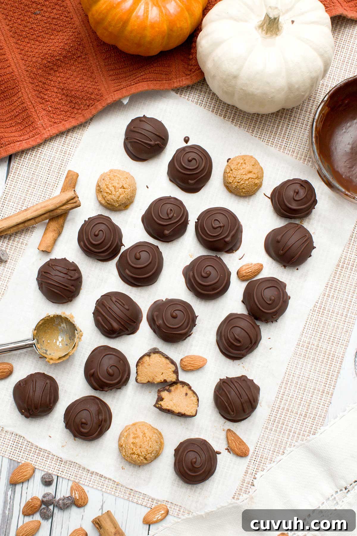 The top view of a batch of chocolate pumpkin truffles dipped in chocolate with swirls on top.