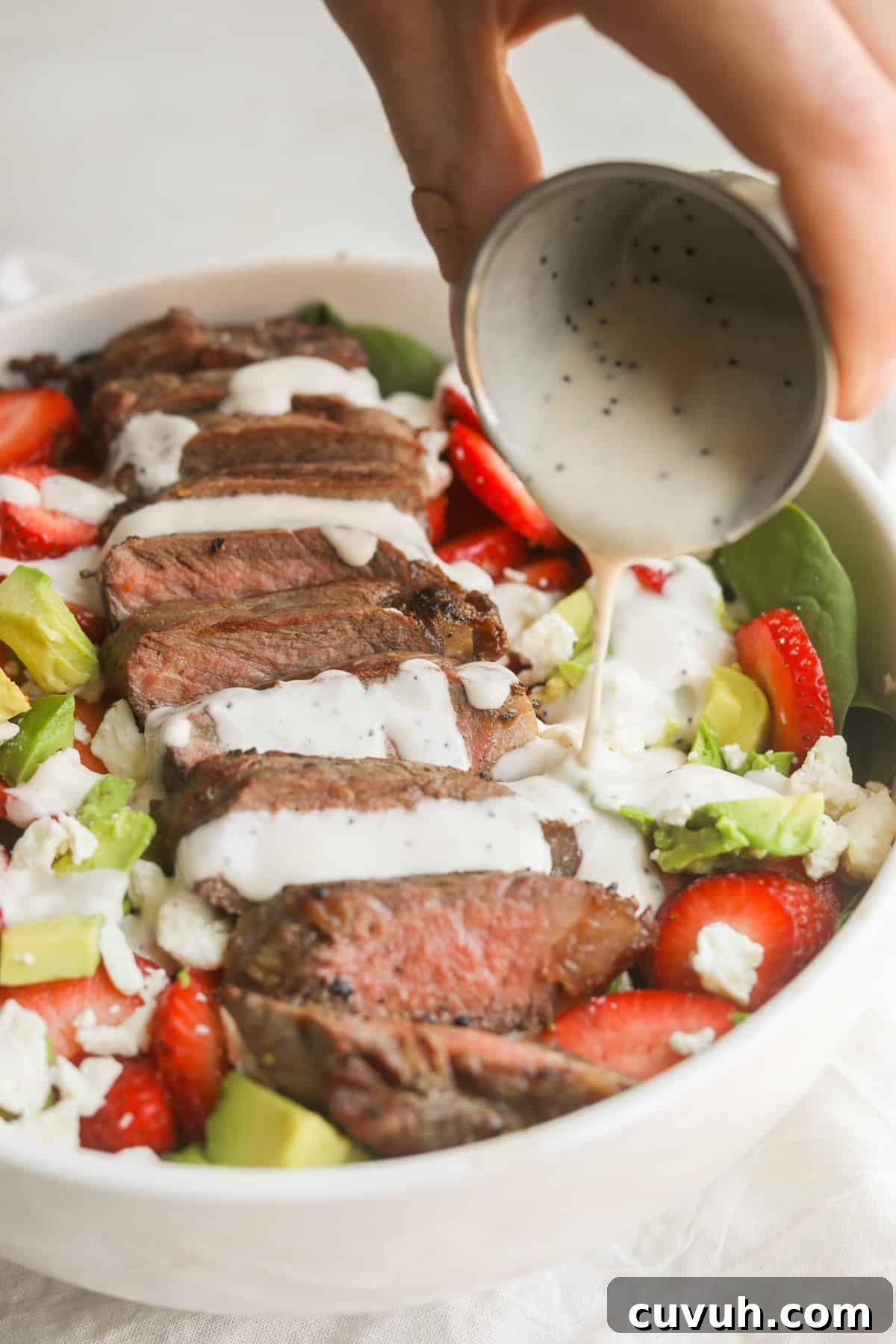Strawberry and Steak Salad with Poppy Seed Dressing 7 pouring dressing on strawberry steak salad