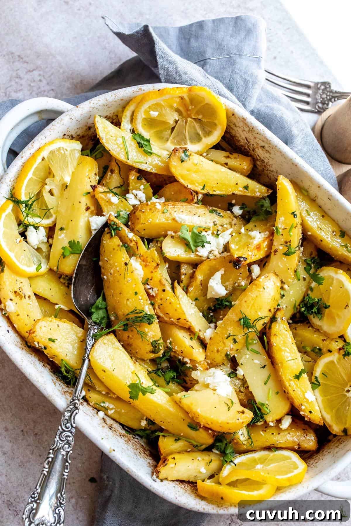 Crispy Lemon-Roasted Potatoes with Garlic and Herbs 2 White ceramic dish with Lemon Roasted Potatoes in it and a grey towel underneath.