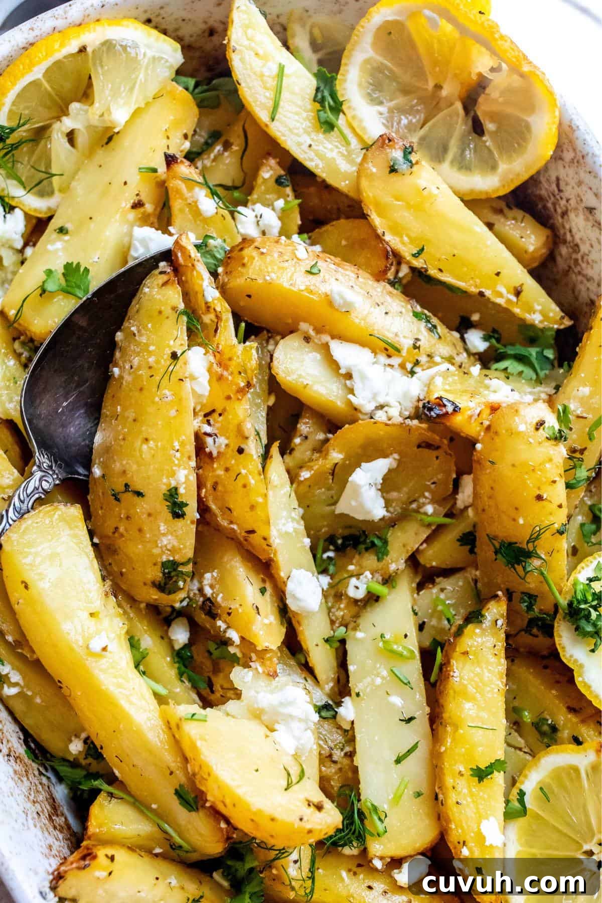 Crispy Lemon-Roasted Potatoes with Garlic and Herbs 5 White ceramic dish with Lemon Roasted Potatoes in it and a grey towel underneath. Up close photo.