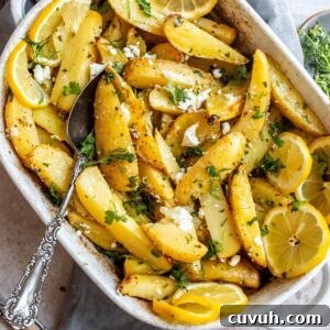 Crispy Lemon-Roasted Potatoes with Garlic and Herbs 6 White ceramic dish with Lemon Roasted Potatoes in it and a grey towel underneath.