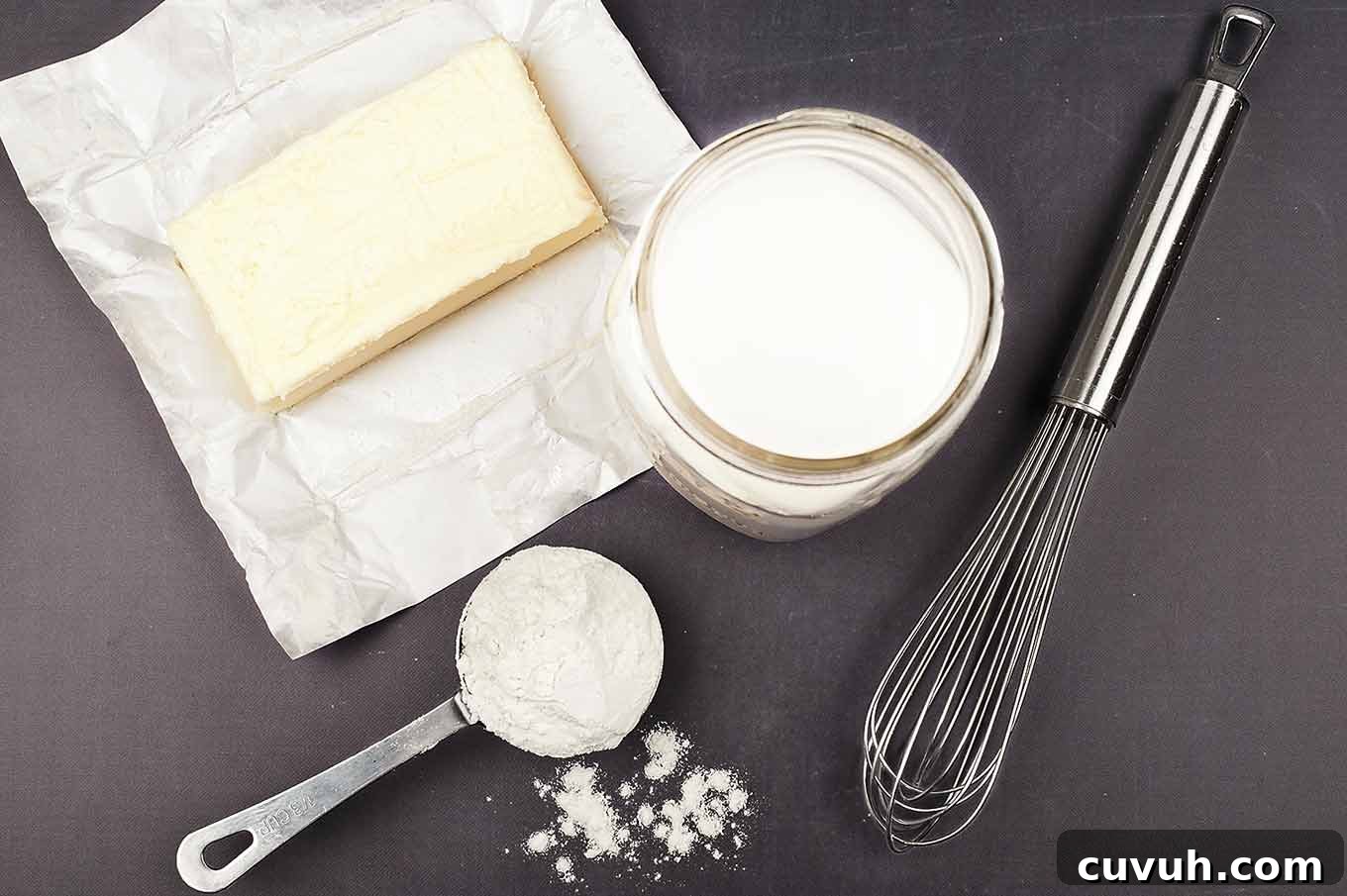Ingredients for béchamel sauce including butter, flour, whole milk, and a whisk for homemade macaroni and cheese.