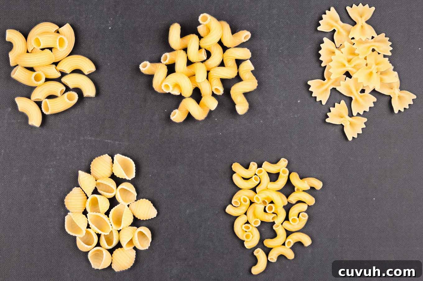 Different pasta shapes including cavatappi, mini farfalle, ridged elbows, pipette, and small shells for homemade macaroni and cheese.