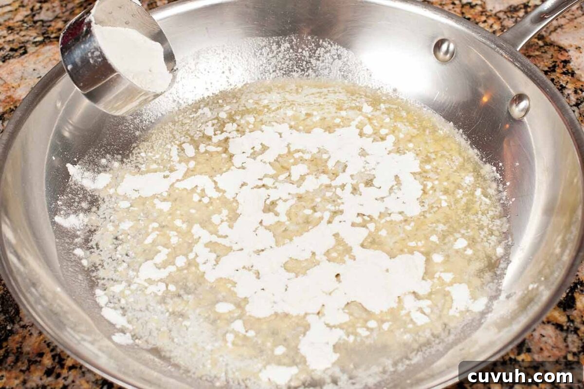 Flour being added to melted butter to make a roux for homemade macaroni and cheese.