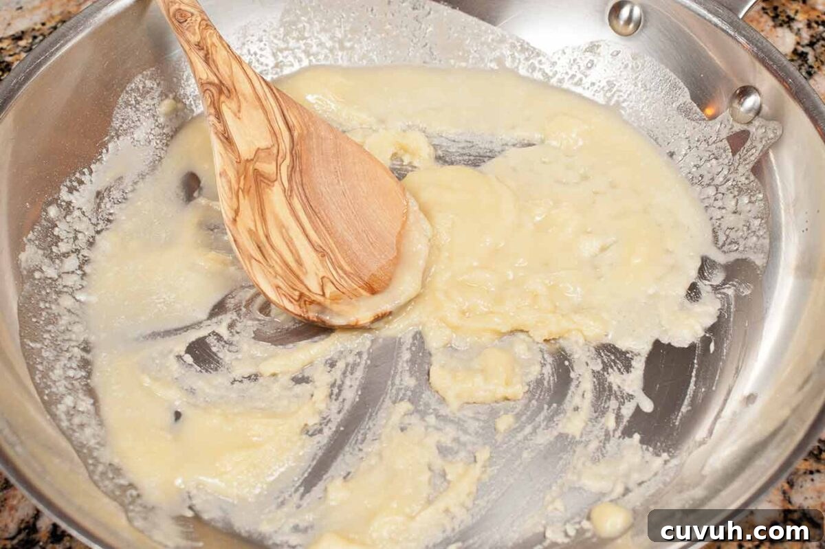 Butter and flour being stirred together to form a roux for homemade macaroni and cheese sauce.